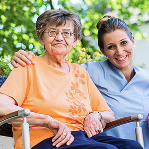 Alltagsbegleiterin sitzt mit einer älteren Frau im Garten und schenkt ihr Nähe und Zuwendung.