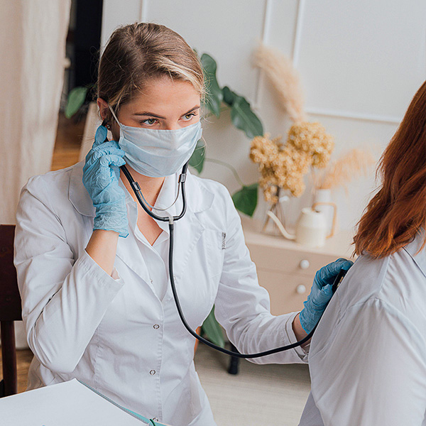 Pflegefachassistenti in der Pflege führt eine medizinische Untersuchung mit dem Stethoskop durch.