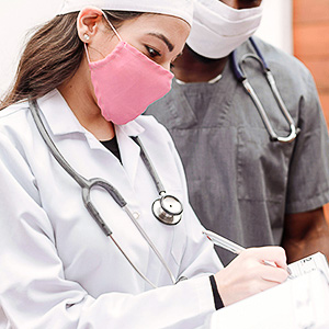 Pflegefachkraft mit Stethoskop und Mundschutz prüft Pflegedokumentation nach aktuellen Expertenstandards und Qualitätsrichtlinien.