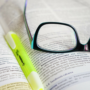 Aufgeschlagenes Fachbuch mit Brille und Textmarker – Symbol für Stundenseminare zu Expertenstandards in der Pflege.