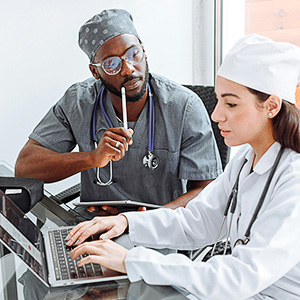 Pflegekraft erklärt einer Kollegin am Laptop fachliche Inhalte – Symbol für Praxisanleitung in der Pflege.