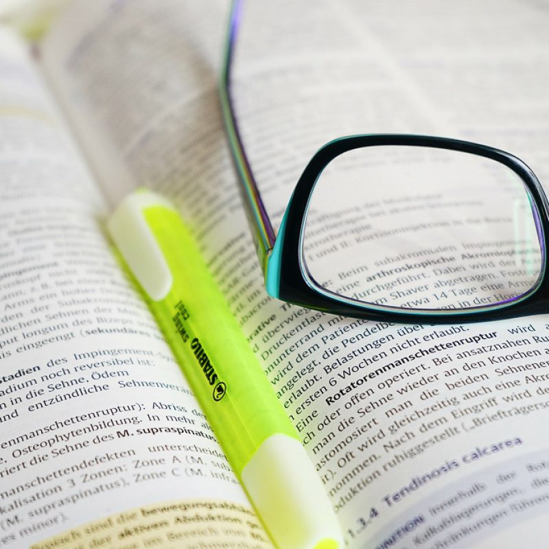 Fachliteratur mit Brille und Textmarker als Symbolbild für die Fortbildung im Gesundheitsberuf.